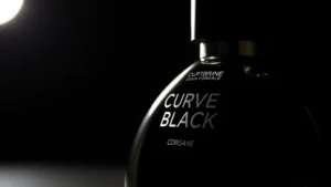 curve black cologne - Close-up of Curve Black cologne bottle with dark liquid visible against moody li